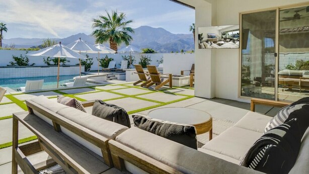 A modern outdoor living area with a pool, lounge chairs, and a view of mountains. - Pool, fire pit & hot tub in La Quinta (La Quinta)