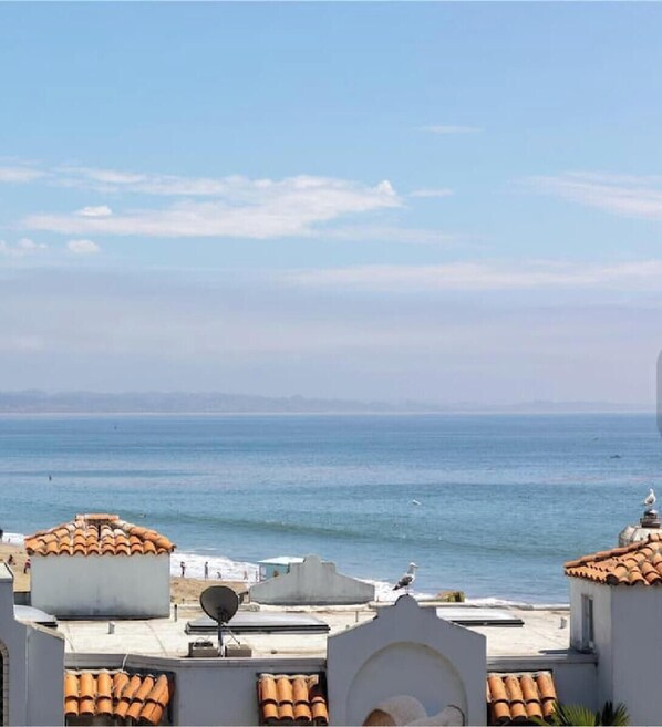 A coastal view with buildings featuring terracotta roofs and satellite dishes.
