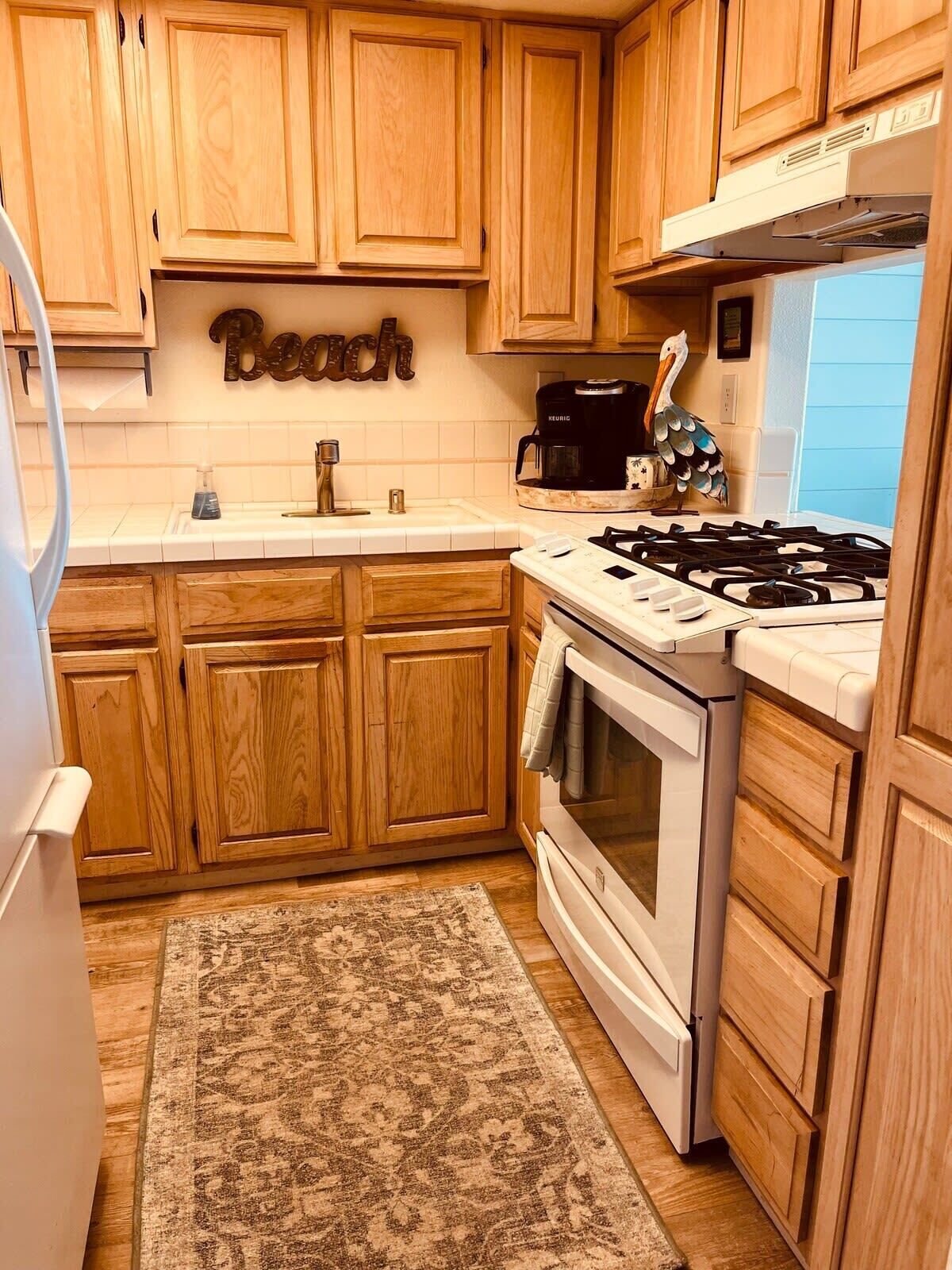A kitchen with wooden cabinets, a stove, a sink, and a coffee maker.