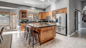 A modern kitchen with wooden cabinets, stainless steel appliances, and a central island with bar stools.