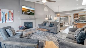 A spacious living room with a fireplace, grey sofas, a coffee table, and a ceiling fan.