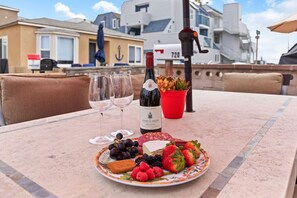 Une table avec une bouteille de vin, des verres et une assiette de fruits et de fromage.