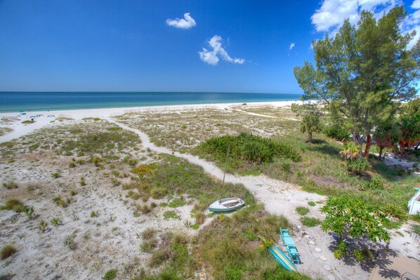 A beach with a sandy path, a small boat, and a row of beach chairs.