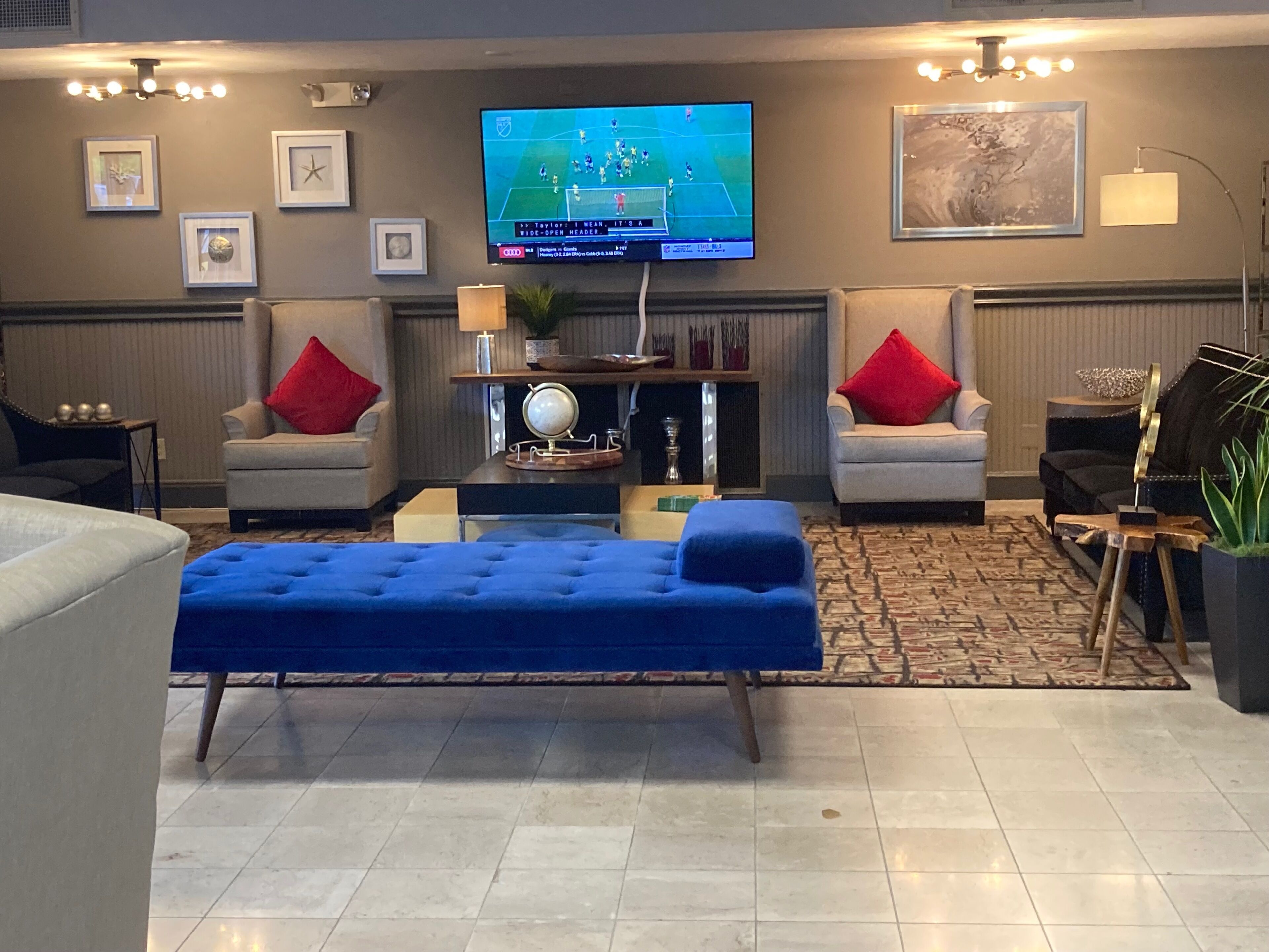 A modern living room with a flat-screen TV, two armchairs, a blue sofa, and a coffee table.