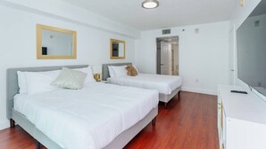 A hotel room with two beds, a TV, and a mirror on the wall. - TC-3406 · Lovely 2BR Rental in the Heart of Brickell (Miami)