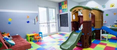 A children's play area with a slide, colorful play mats, and a playhouse.