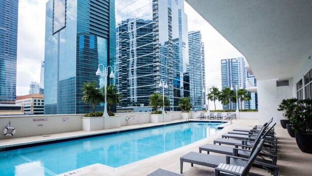 A rooftop pool area with lounge chairs and a view of modern high-rise buildings. - TC-3406 · Lovely 2BR Rental in the Heart of Brickell (Miami)