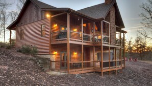 A two-story log cabin with a balcony, a chimney, and a porch area. - Hot tub, firepit, outdoor living, comfy beds, and more! - 5 O'Clock Somewhere (Mineral Bluff)