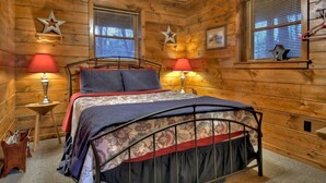 Ein Schlafzimmer in einer Holzhütte mit einem Metallbettgestell, zwei Nachttischlampen und Sternen an den Wänden.