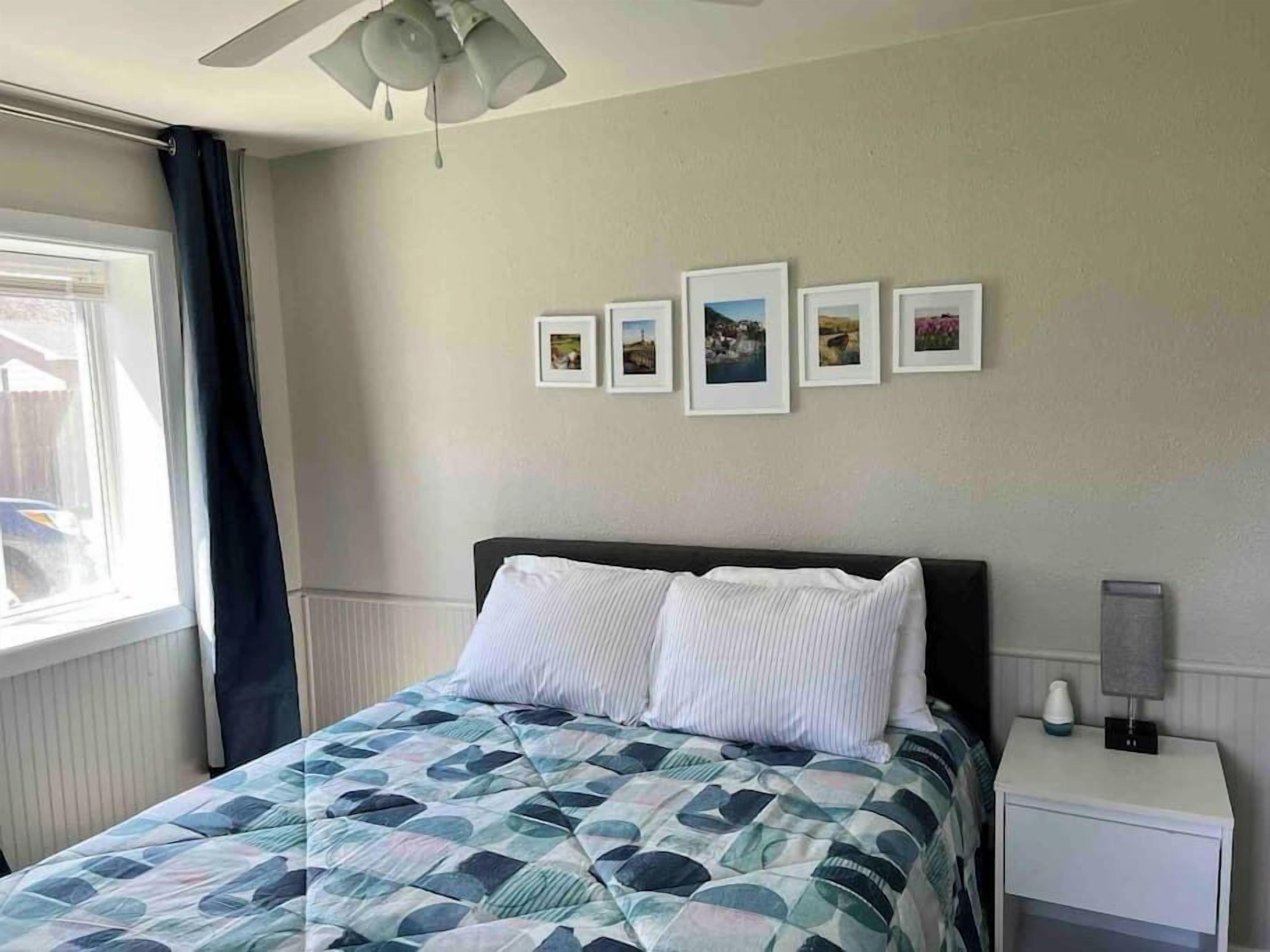 A bedroom with a bed, a nightstand, a lamp, and a ceiling fan.