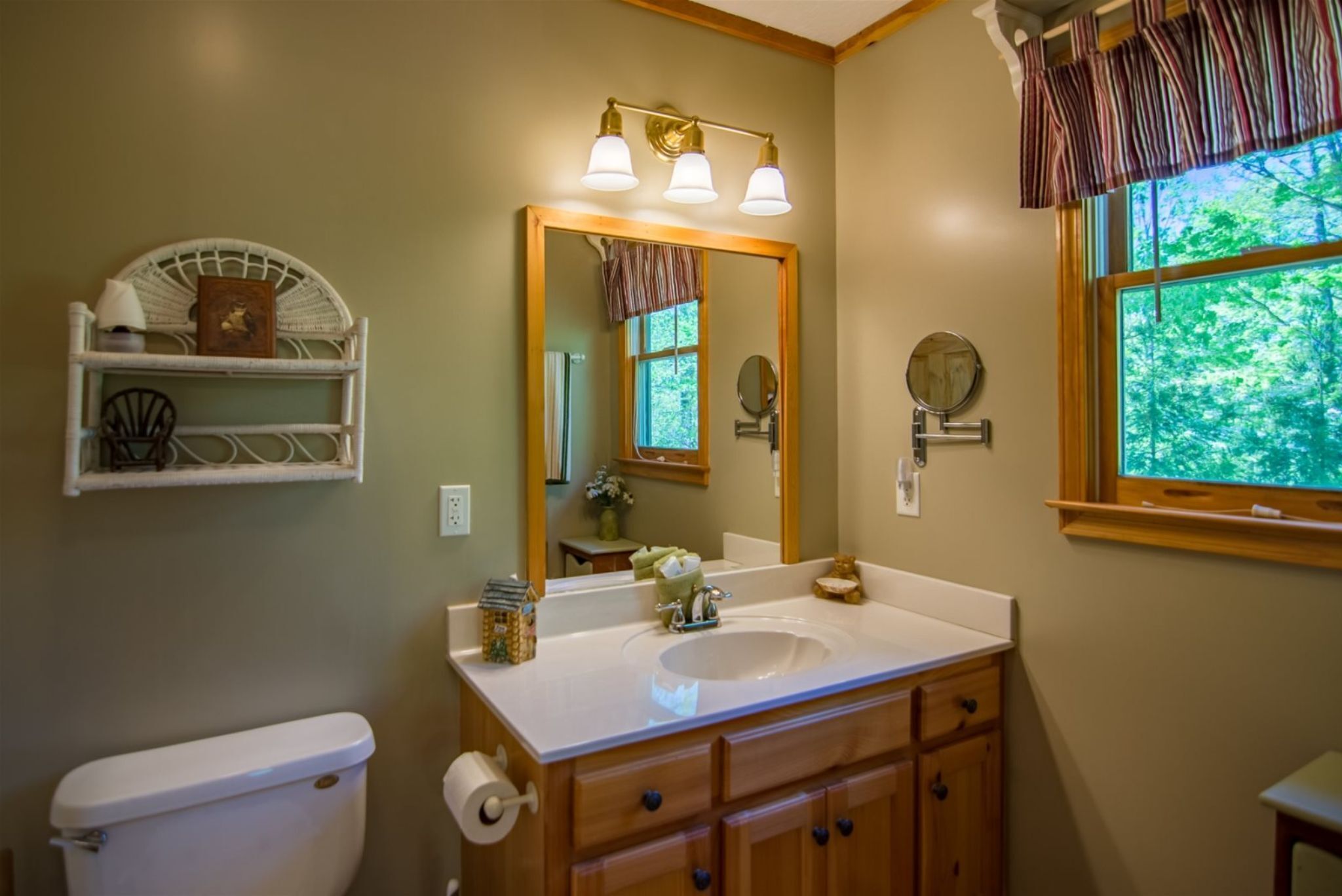 A bathroom with a white sink, wooden vanity, and a large mirror.