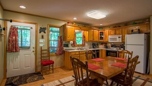 A kitchen with wooden cabinets, a microwave, a refrigerator, and a dining table with chairs.