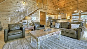 A log cabin interior with a staircase, leather furniture, a wooden coffee table, and a kitchen area. - Nearby hikes + a hot tub! - Appalachian Sunrise (Blue Ridge)