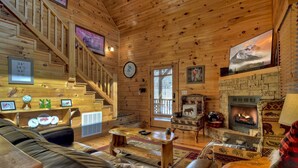 A log cabin interior with a fireplace, wooden staircase, and a cozy seating area. - Scenic Views, Hot Tub Soaks, Firepit Roasts, Cookouts & Nearby Adventures - Cardinal's Crossing (Morganton)