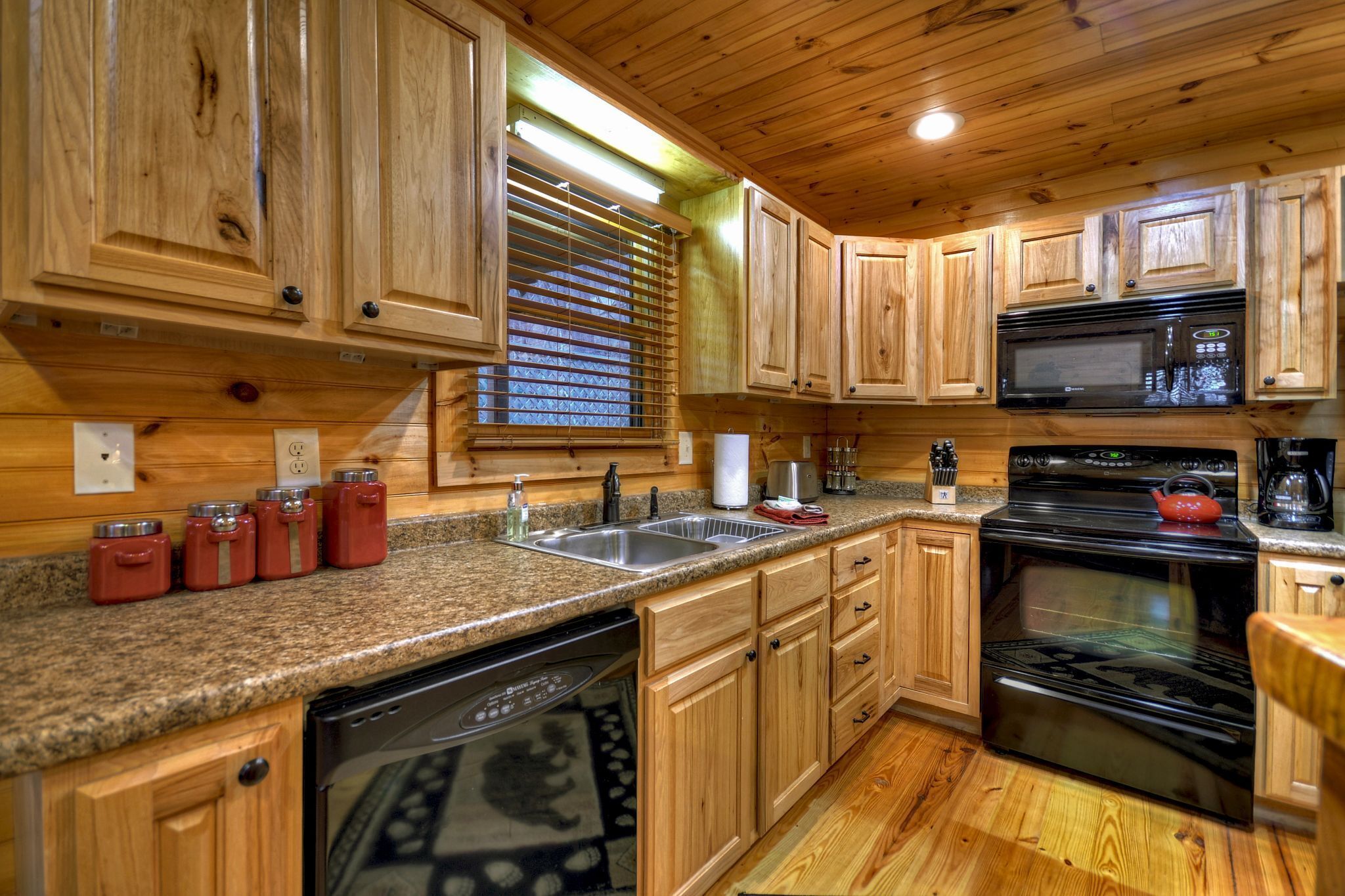 A kitchen with wooden cabinets, granite countertops, a dishwasher, a stove, and a microwave.