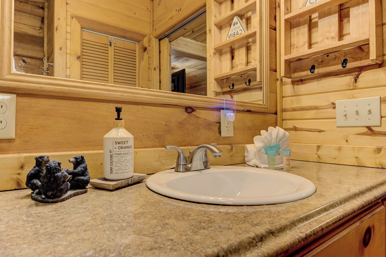 A wooden cabin bathroom with a sink, mirror, and shelves.