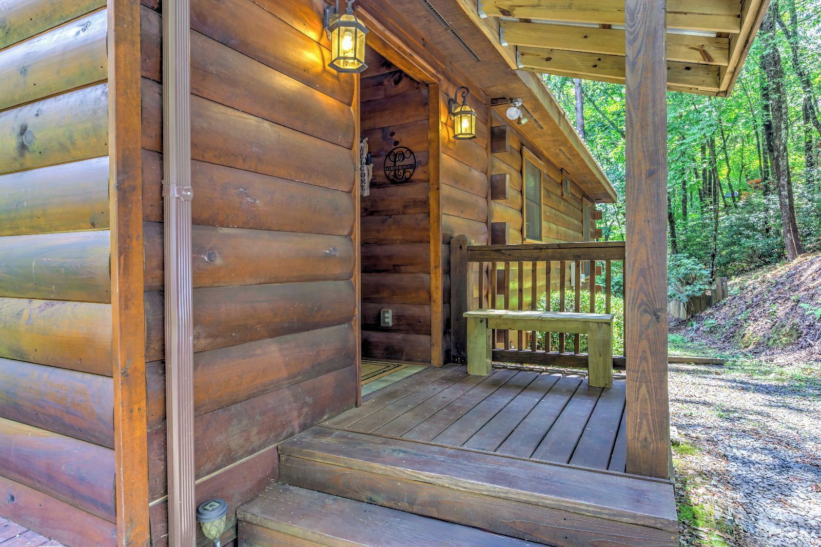 A wooden cabin with a porch and a bench.