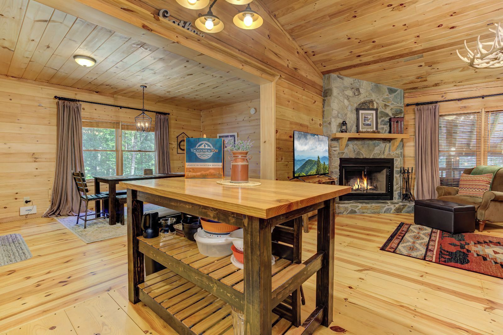 A wooden cabin interior with a dining area, fireplace, and stone wall.