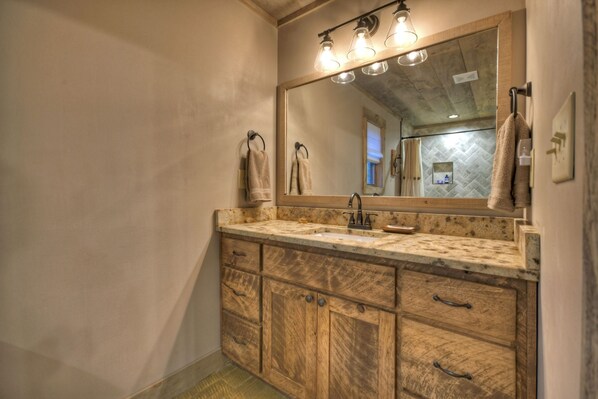 Un baño con tocador de madera, un espejo grande y una pared con motivo de espiga.