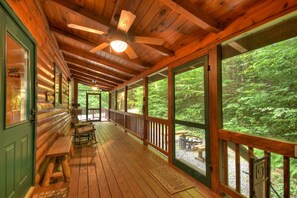 A wooden cabin with a porch, large windows, and a ceiling fan.