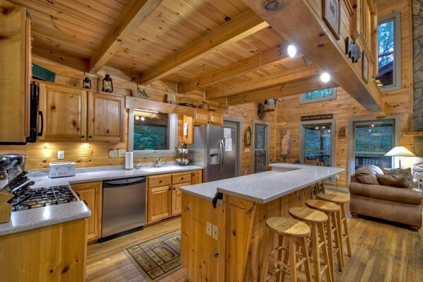 A wooden cabin interior with a kitchen, bar area, and seating.