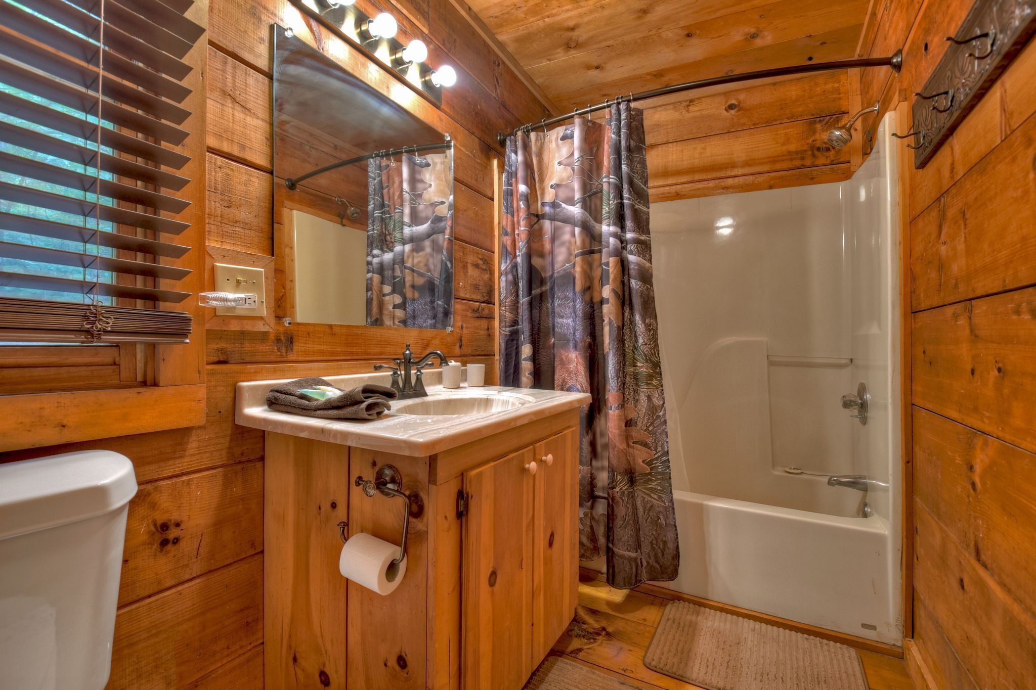 A wooden cabin bathroom with a sink, toilet, and shower.