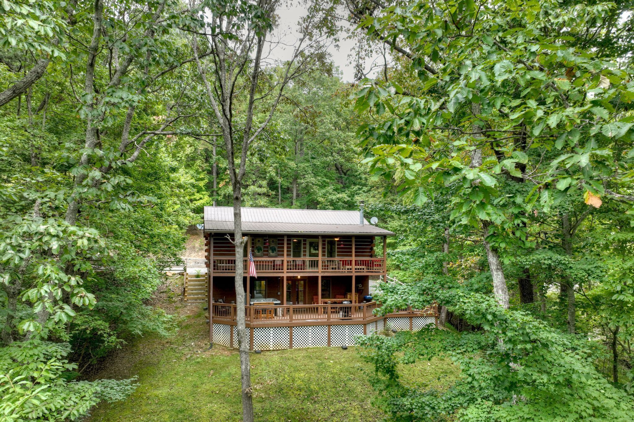 Une cabane en bois à deux étages, entourée d’une forêt dense.