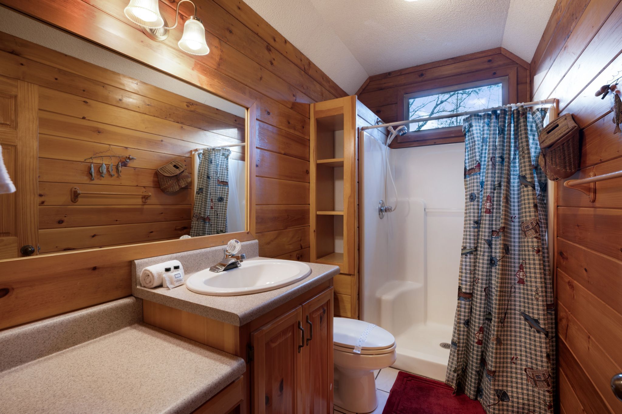 Une salle de bain rustique, aménagée dans une cabane en bois, avec un lavabo, des toilettes et une douche.