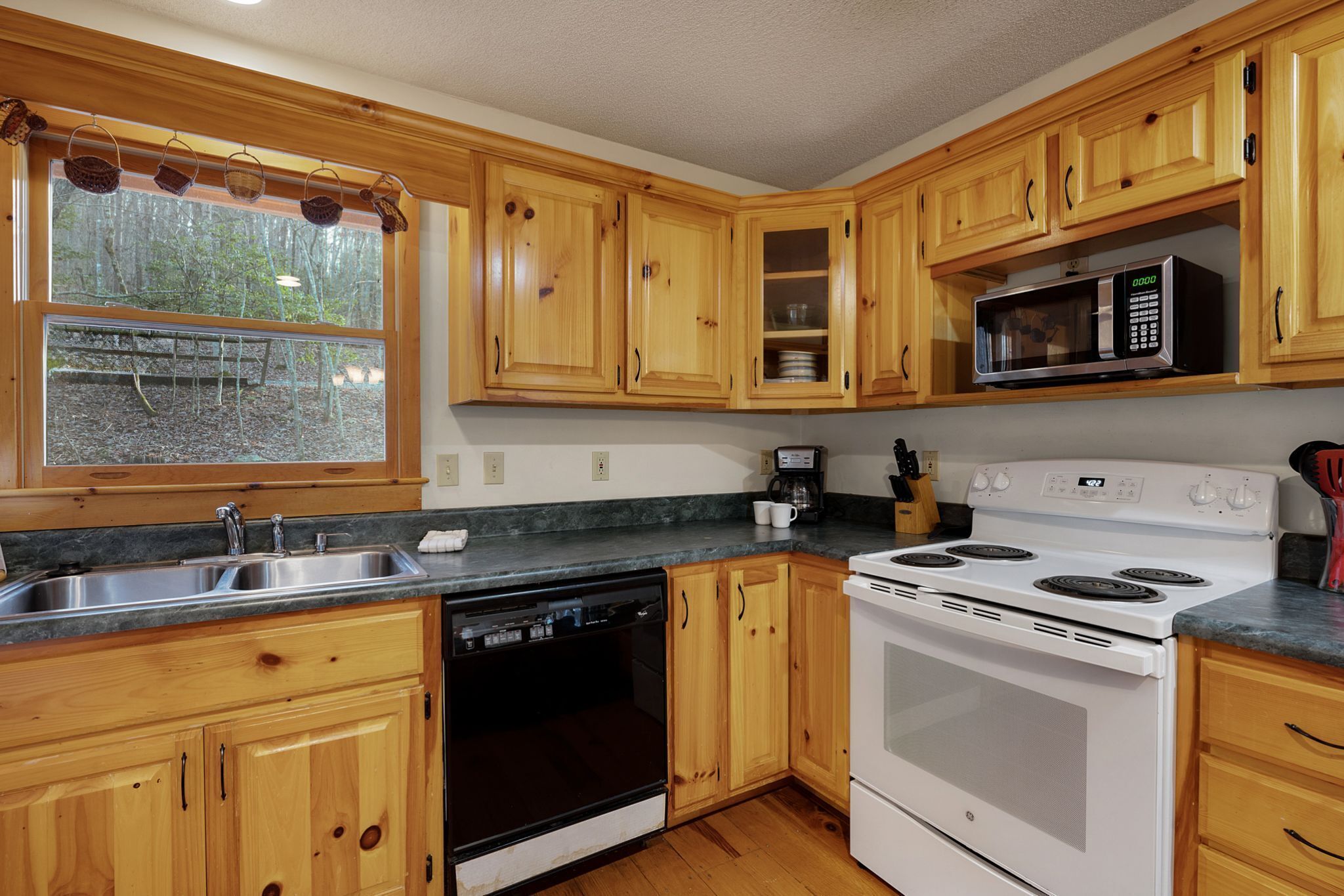 A kitchen with wooden cabinets, a dishwasher, a stove, and a microwave.