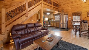 L’intérieur d’un chalet en bois comprend un canapé en cuir, une table à manger et un coin cuisine.