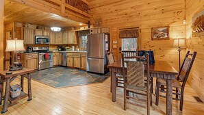 L’intérieur d’un chalet en bois comprend une cuisine, un coin repas et une cheminée.