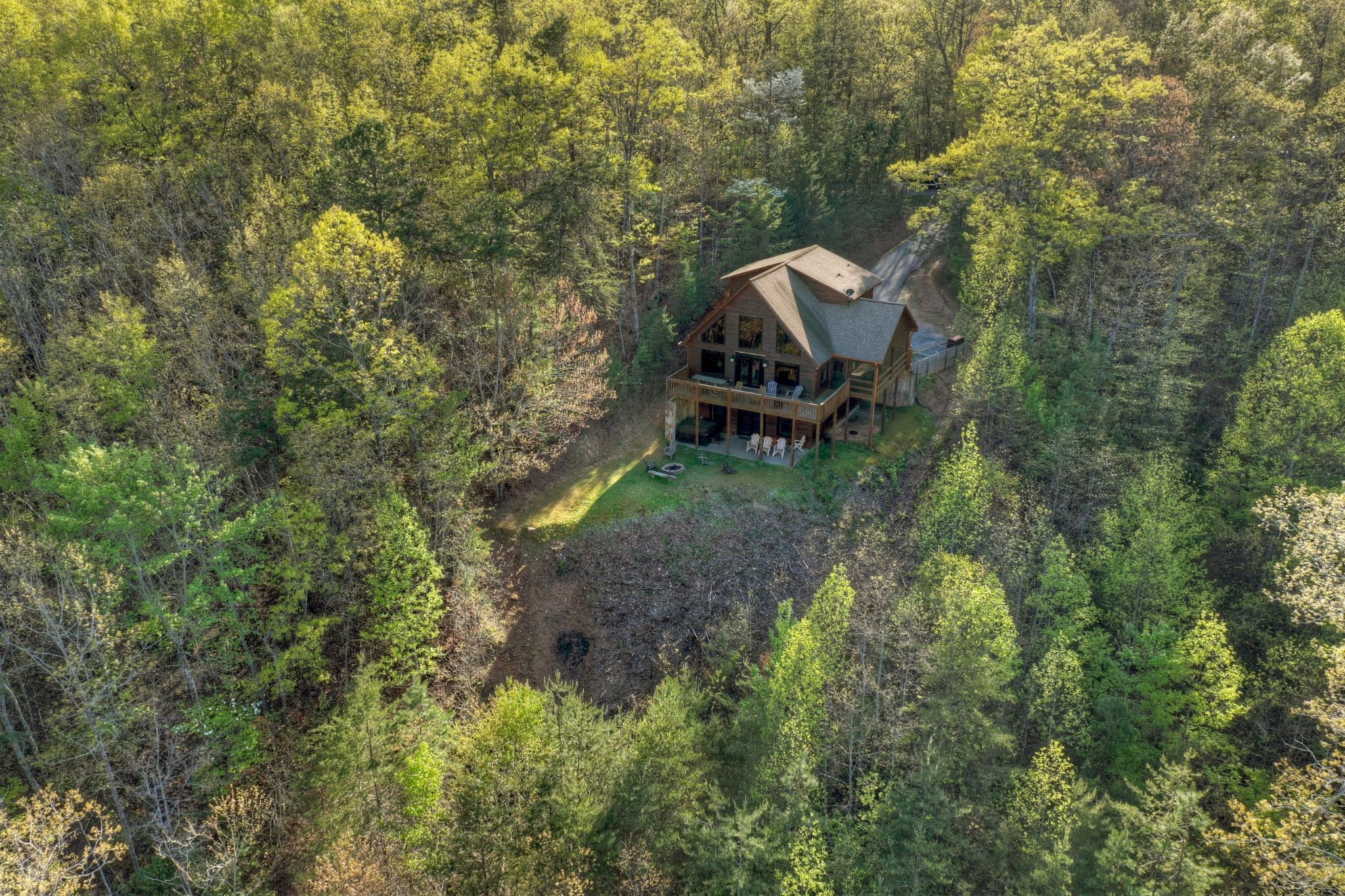 Una cabana envoltada de bosc dens, amb un gran balcó i zona d'estar a l'aire lliure.