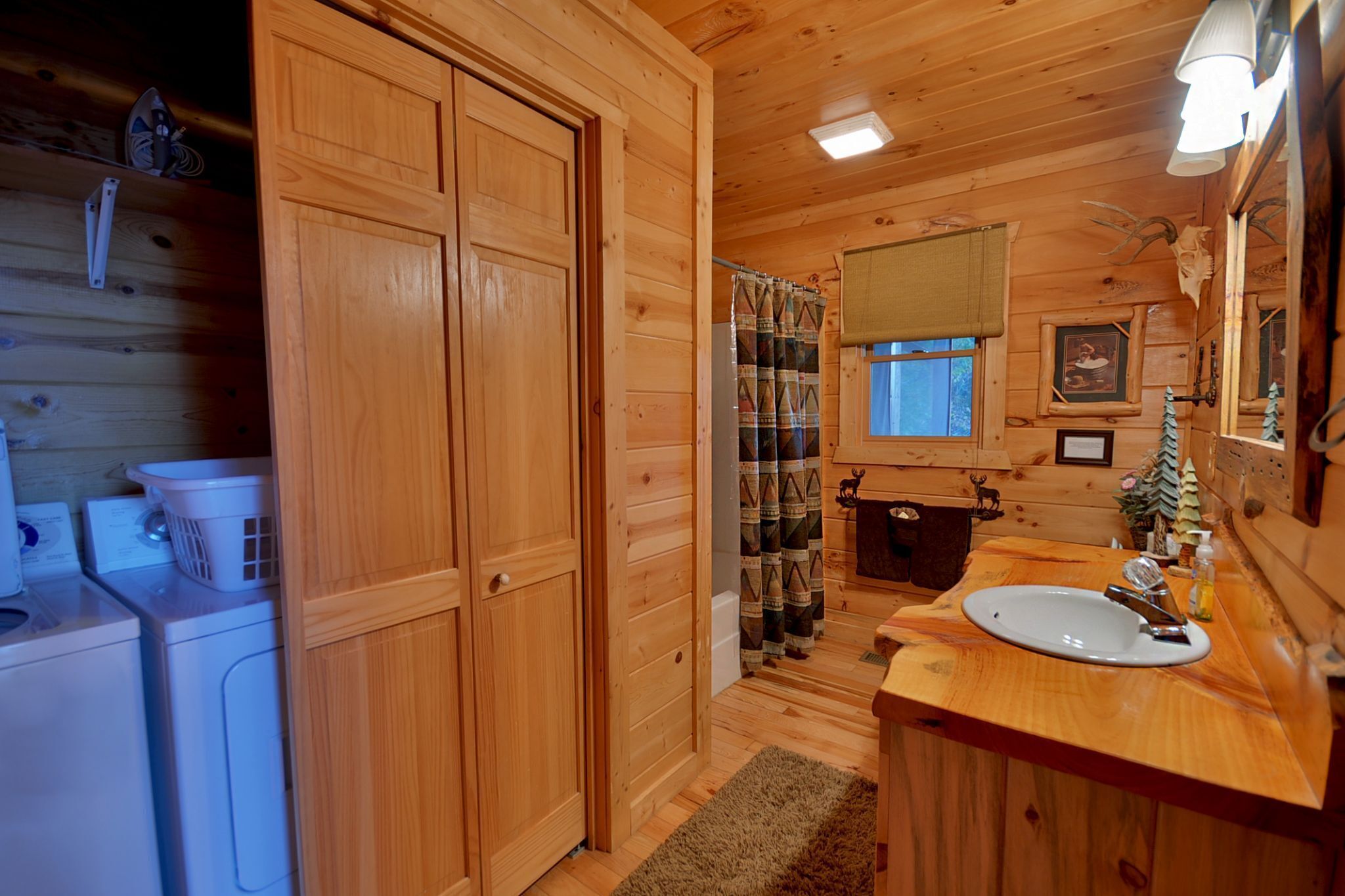 Baño de cabaña de madera con lavabo, espejo y cortina de ducha.