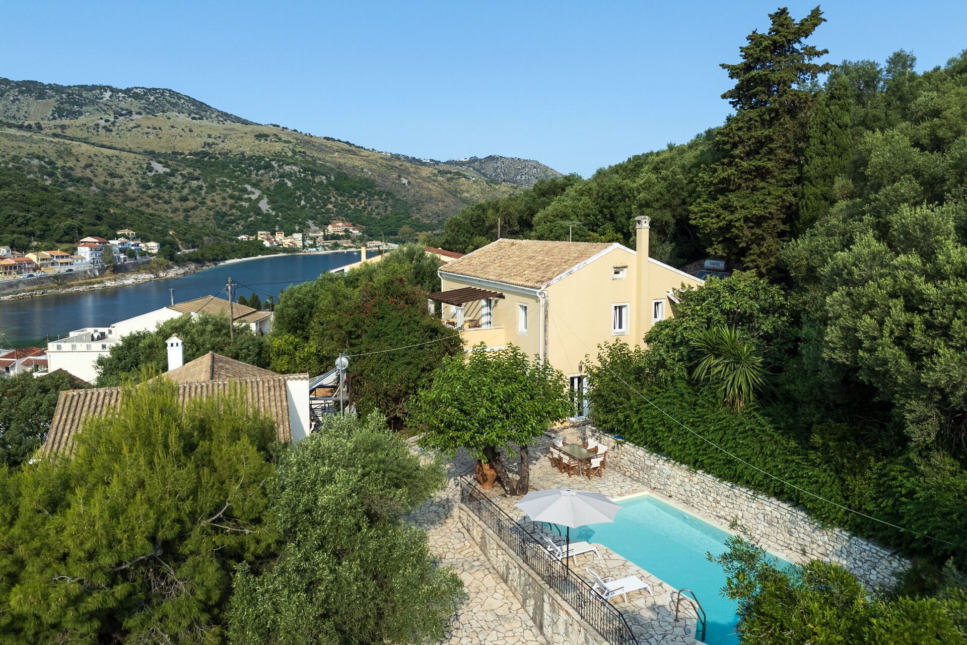 Una casa amb piscina, envoltada d'arbres i amb vistes a un cos d'aigua.