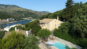 Ein Haus mit Schwimmbad, umgeben von Bäumen und mit Blick auf ein Gewässer.