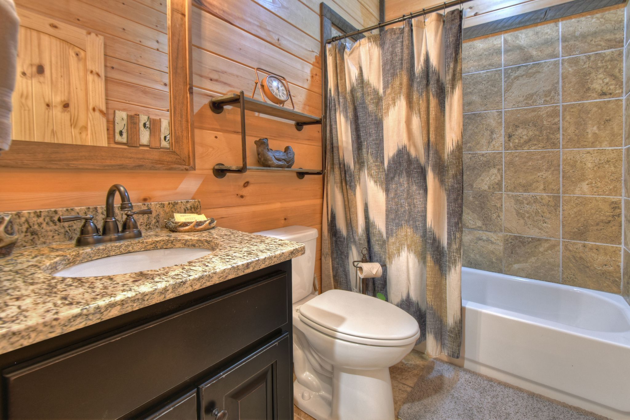 A bathroom with a granite countertop sink, a white toilet, and a bathtub.