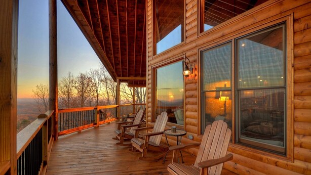 Eine Holzhütte mit Veranda, großen Fenstern und Sitzgelegenheit im Freien.