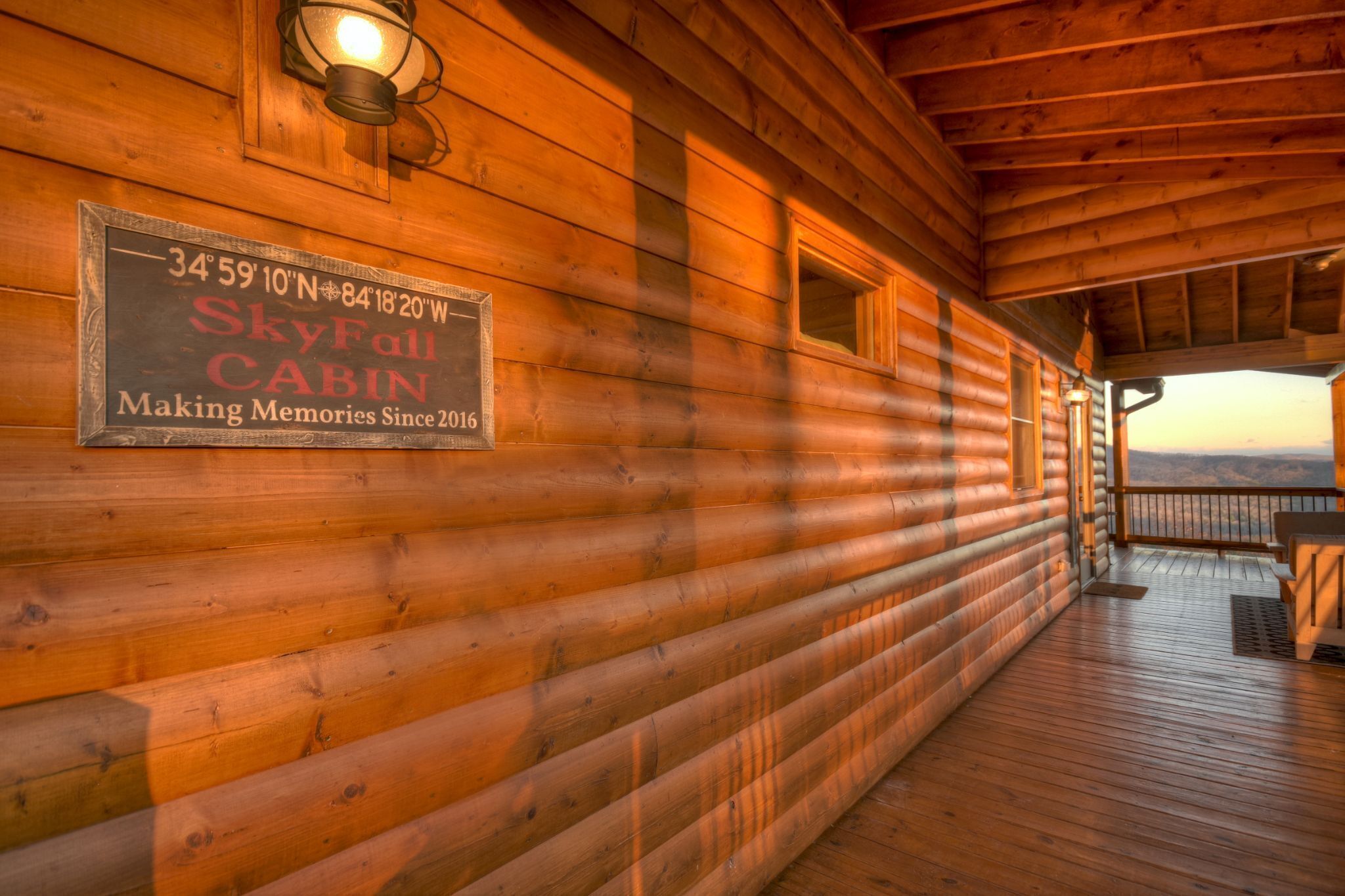 Une cabane en bois, sur laquelle est apposée une plaque indiquant ses coordonnées et son nom, « SkyFall Cabin », et qui offre une vue sur les montagnes.