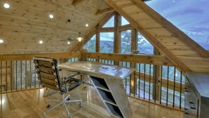 Een ruime loft met hoge plafonds, een groot bureau en uitzicht op het omliggende landschap.