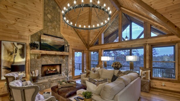 A cozy log cabin interior with a fireplace, comfortable seating, and large windows offering views of the outdoors. - Relax in private rustic luxury! - A Starry Night (Cherry Log)