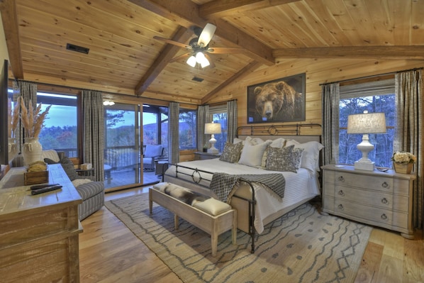 Une chambre confortable avec un grand lit, un banc, une commode et un ventilateur de plafond.