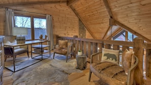 A cozy cabin interior with wooden walls, a dining table, chairs, and a rustic sofa. - Relax in private rustic luxury! - A Starry Night (Cherry Log)