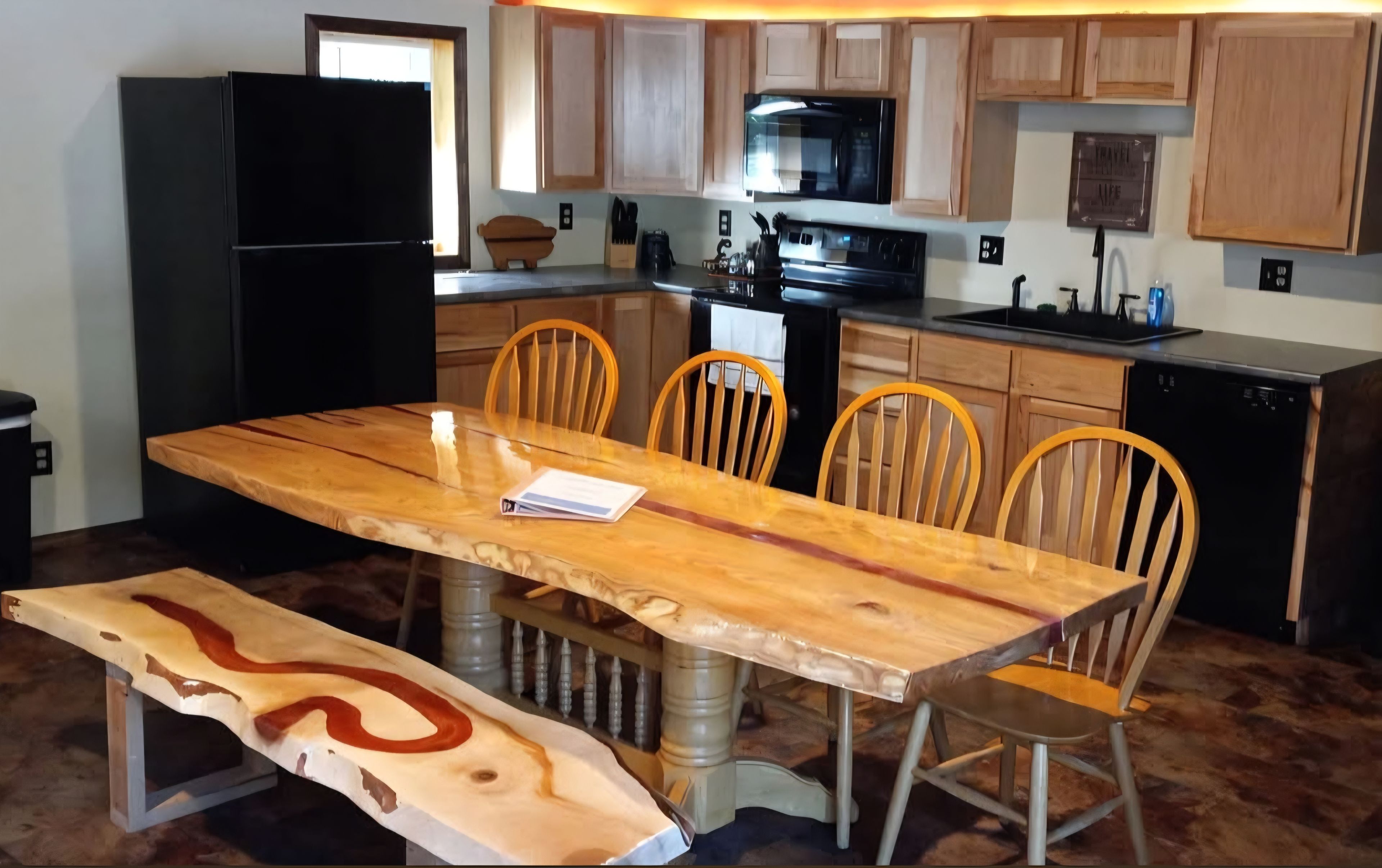 A kitchen with a wooden table, chairs, a refrigerator, a microwave, and a dishwasher.