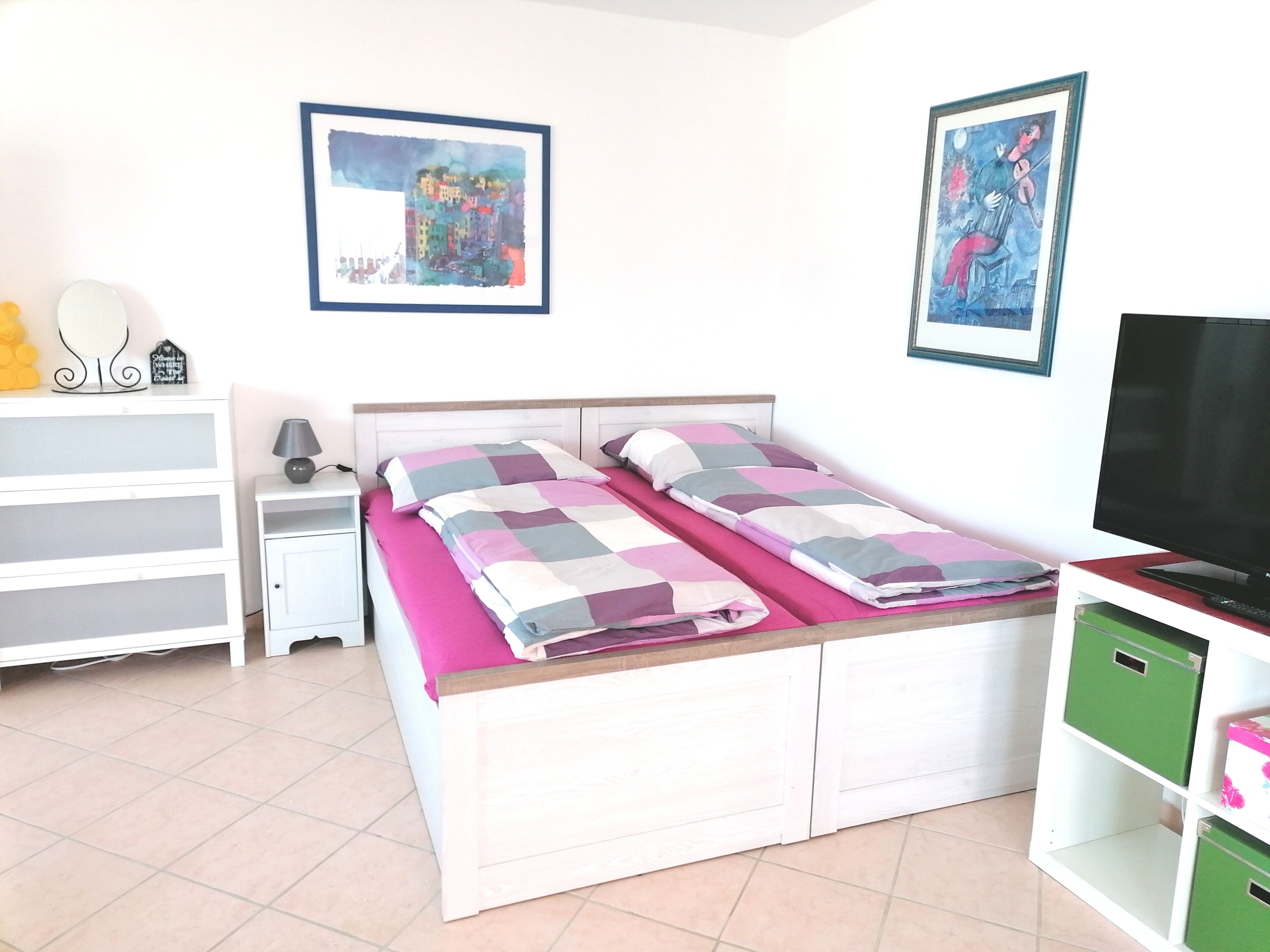 Une chambre à coucher comprenant un lit, une table de chevet, un téléviseur et des meubles de rangement.