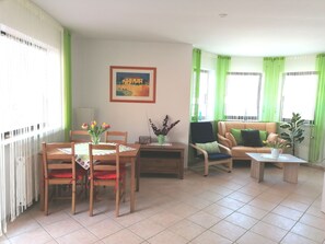 Una sala de estar con una mesa de comedor, sillas, un sofá y un cuadro en la pared.
