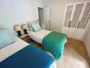 Ein Zimmer mit zwei Betten, einem Kleiderschrank und einer Tür.