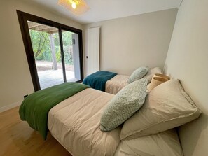 Une chambre avec une grande fenêtre, un lit garni de plusieurs oreillers et un plancher en bois.