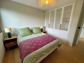 A bedroom with a bed, nightstands, a lamp, a wardrobe, and a hanging light fixture. - Attractive Villa with panoramic bay views A0303 (Lège-Cap-Ferret)
