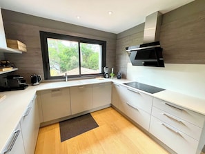 Eine moderne Küche mit großem Fenster, integrierten Geräten und minimalistischem Design.