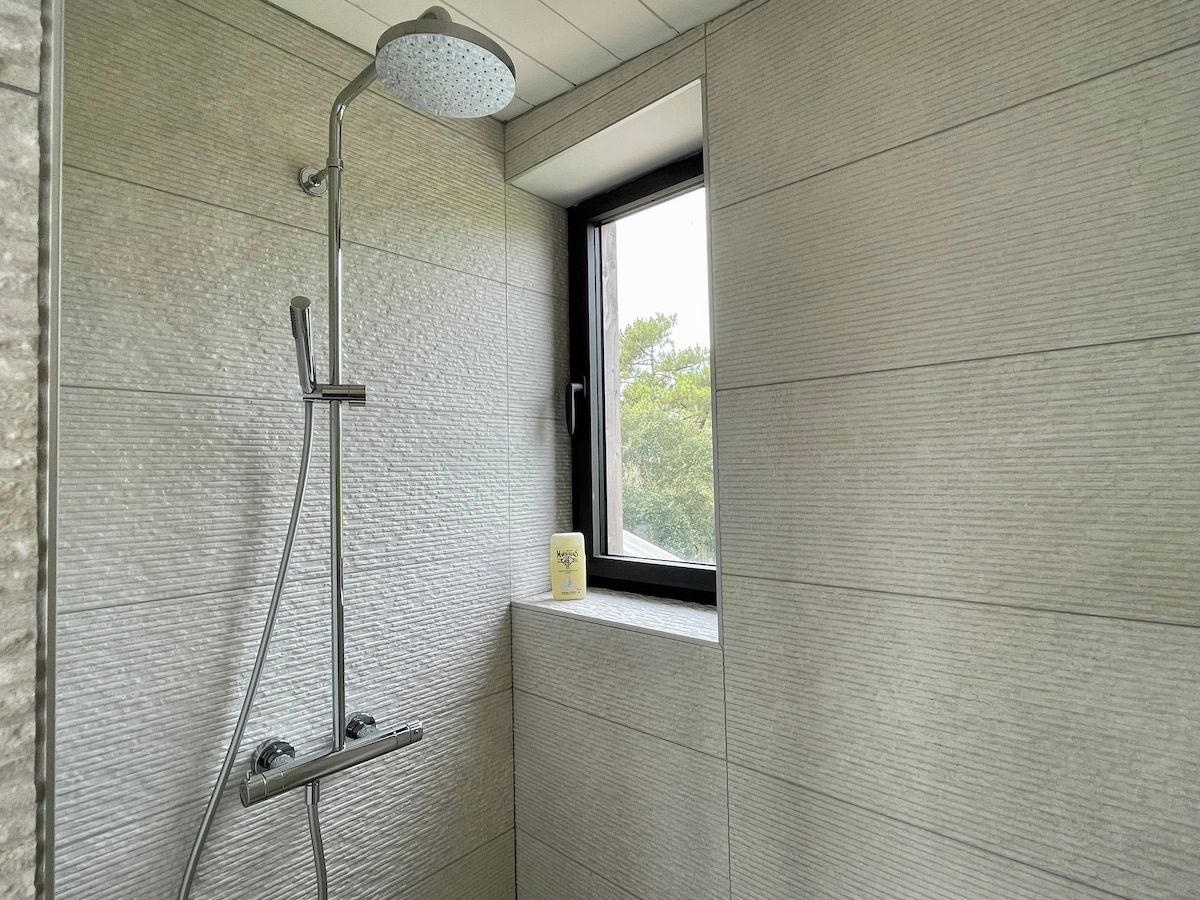 Une salle de bain avec une douche, une fenêtre et un distributeur de serviettes.